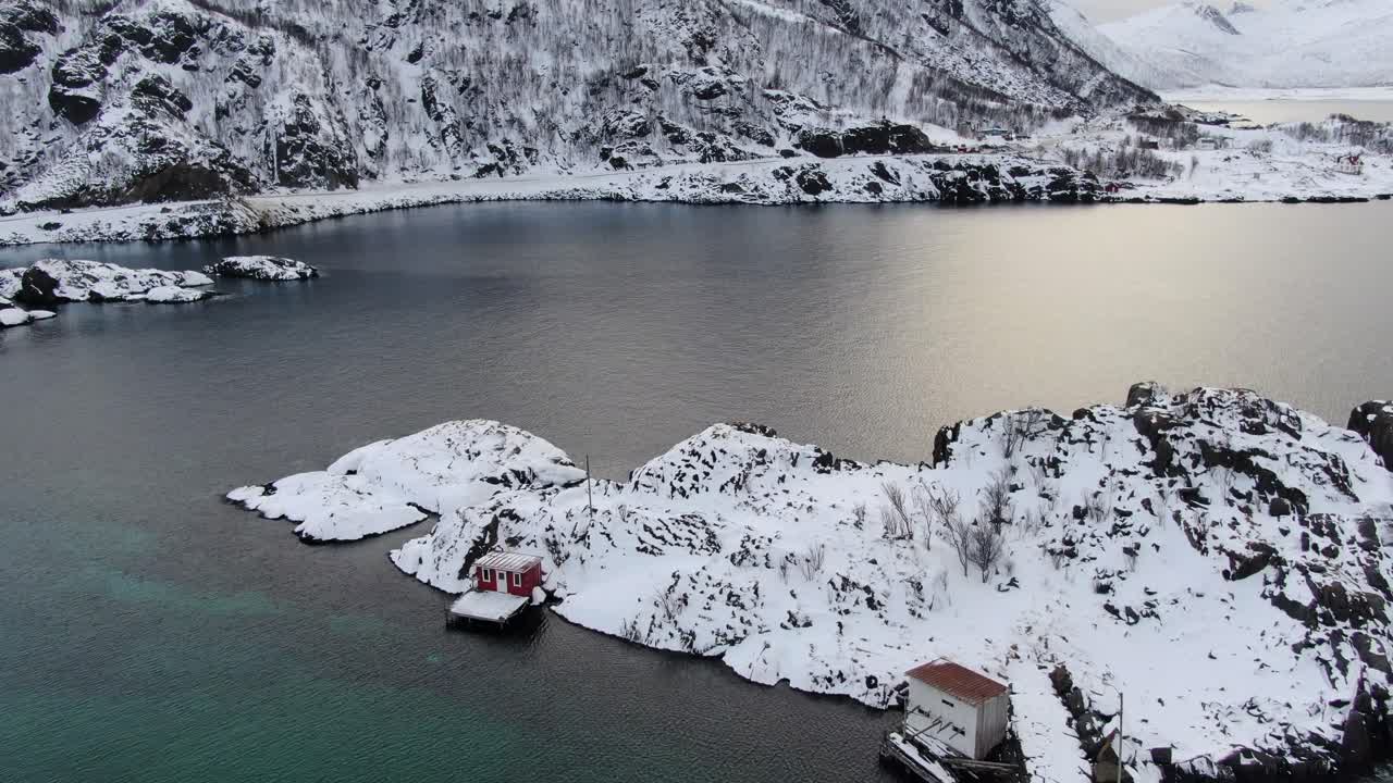 vista del avión no tripulado en el área de tromso en invierno volando sobre un mar azul claro con pequeñas casas en noruega e islas nevadas