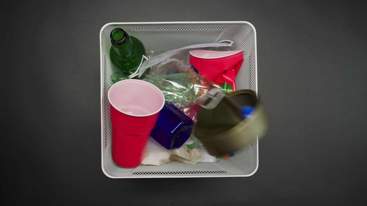 Various Trash Items Dropped into a White Recycling Bin