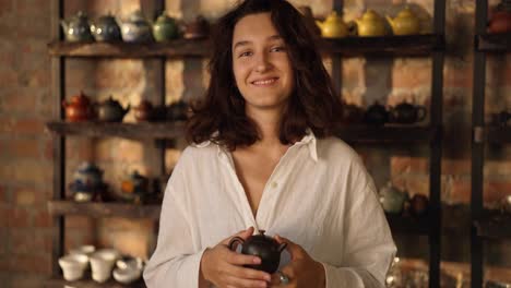 mujer sonriente sosteniendo una tetera en una tienda de té