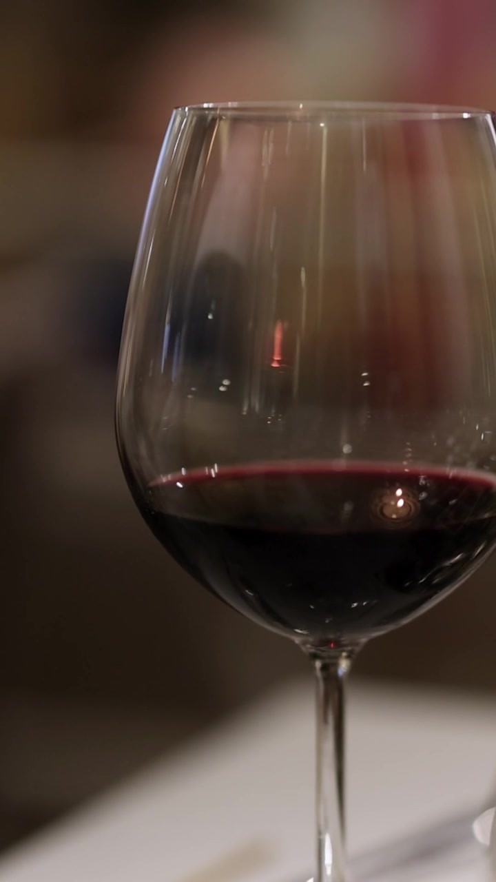 Uma tomada vertical centralizada de uma taça de vinho tinto sobre uma mesa com bokeh suave