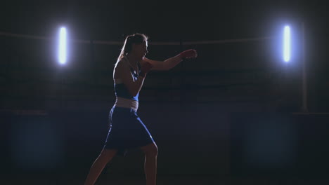 a strong athletic, woman boxer, boxing at training on the black background. sport boxing concept with copy space.