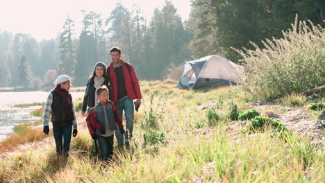 parents on a camping trip with two kids walking near a lake