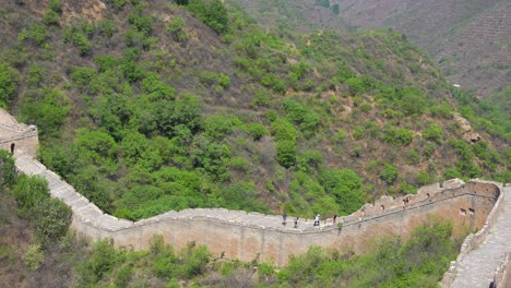group of hikers moves along the great wall at jinshanling, under a bright sunny sky