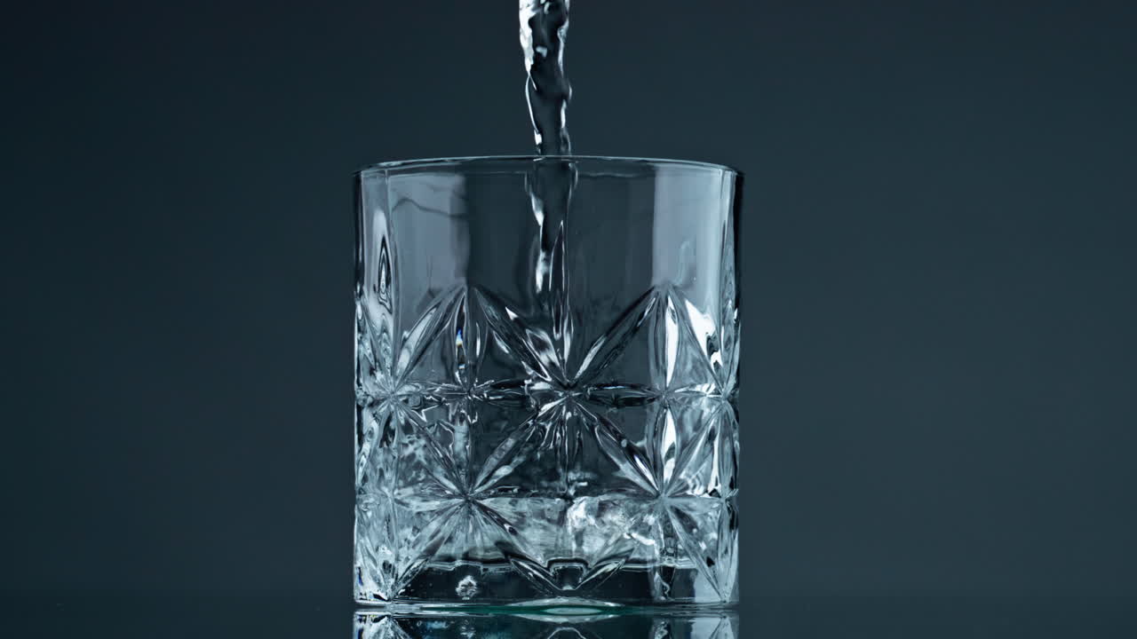 Water stream filling glass closeup. Crystal clear beverage pouring beautiful cup