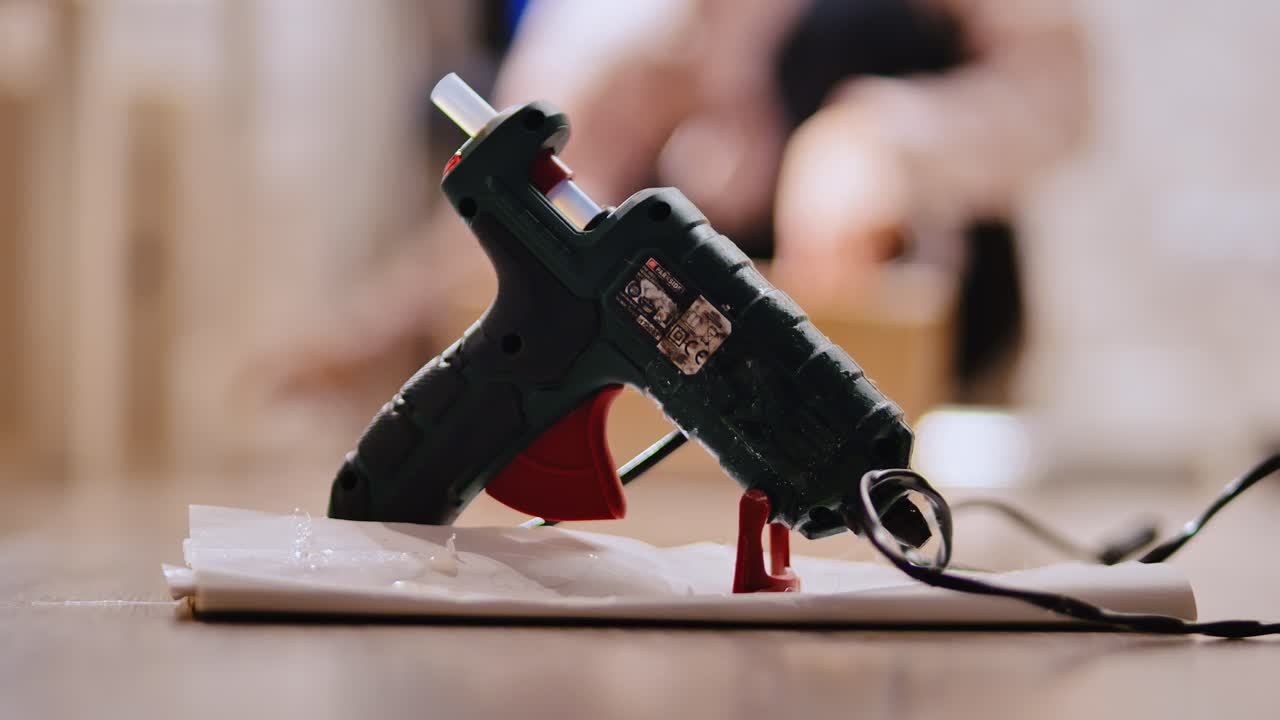 Pistola per colla a caldo che si riscalda sul tavolo mentre una persona lavora a un progetto artigianale