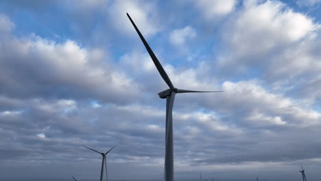 Aerial-view-rising-up-stationary-renewable-wind-turbines-on-cloudy-Barcelona-farmland