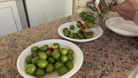 Person-is-adding-salad-ingredients-from-glass-can-to-small-white-plates