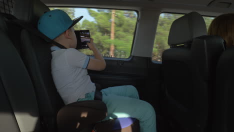 boy taking pictures with cell when traveling by car