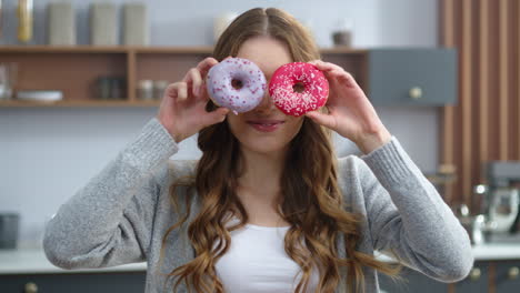 woman playing with cakes indoors. funny girl having fun with colorful donuts.