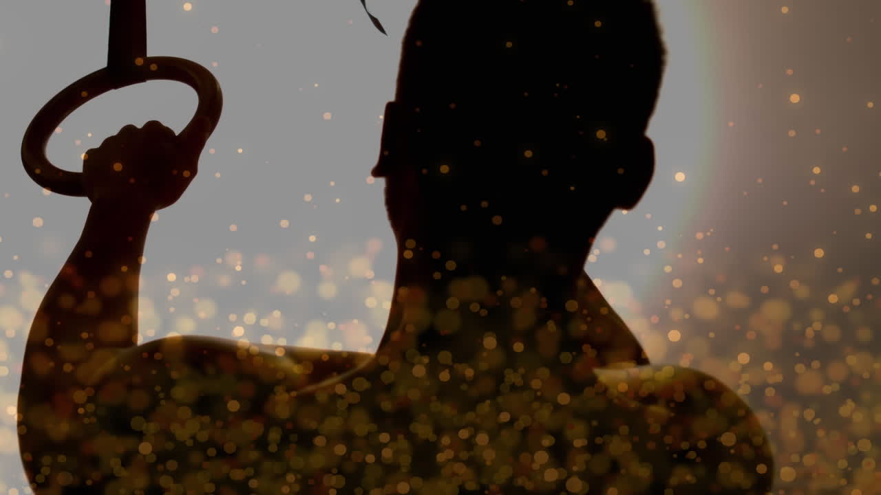 황금빛으로 빛나는 반점이 운동하는 사람의 실루 ⁇ 에 대해 움직이는 디지털 복합 비디오