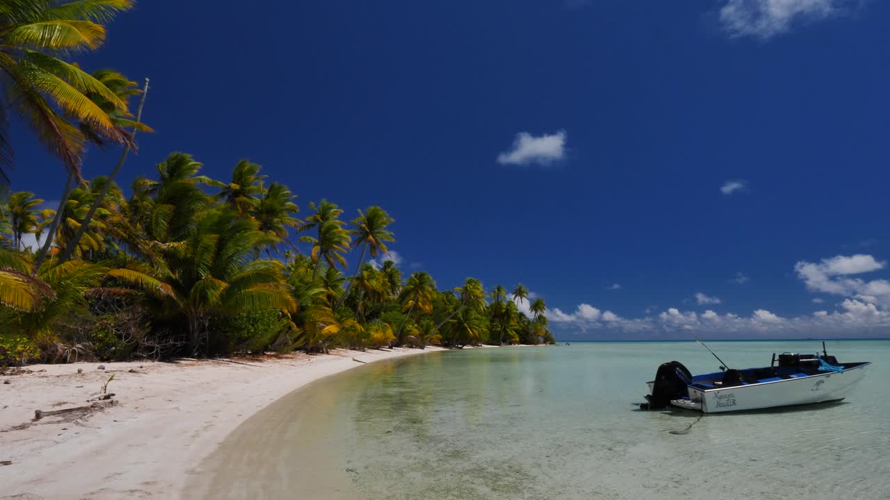 The most beautiful tropical beach of the atoll of Fakarava, French Polynesia with a fishing boat floating on the crystal clear water of the blue lagoon