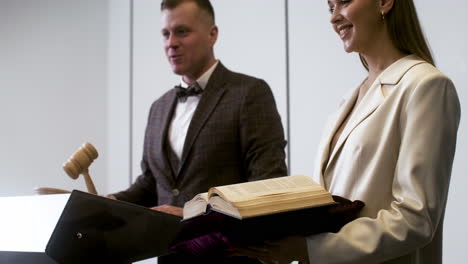 hombre en traje elegante con martillo y mujer sosteniendo un libro