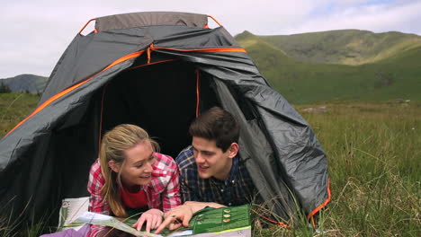 happy couple reading map lying in their tent