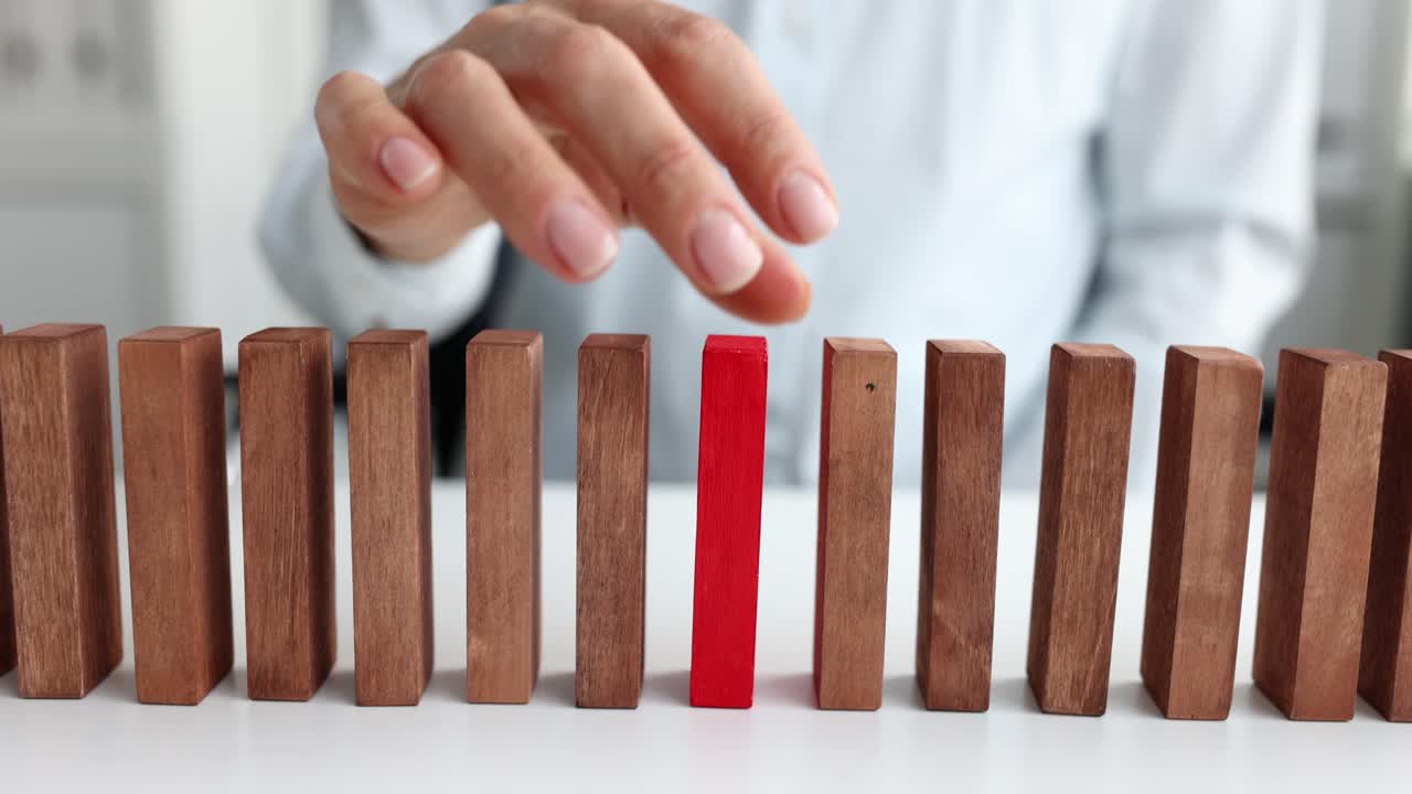 Hand Interacting with a Red Wooden Block Among Brown Blocks