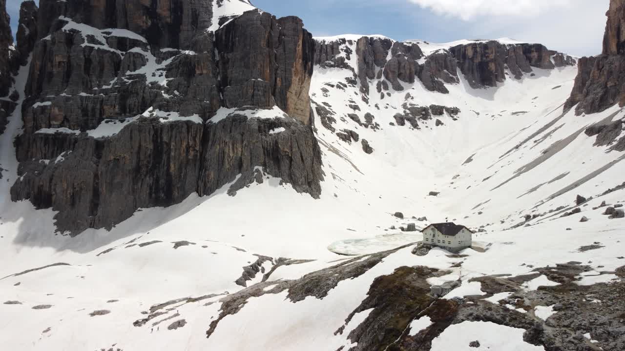 높은 돌로마이트 봉우리로 둘러싸인 눈 인 계곡의 산에 있는 집