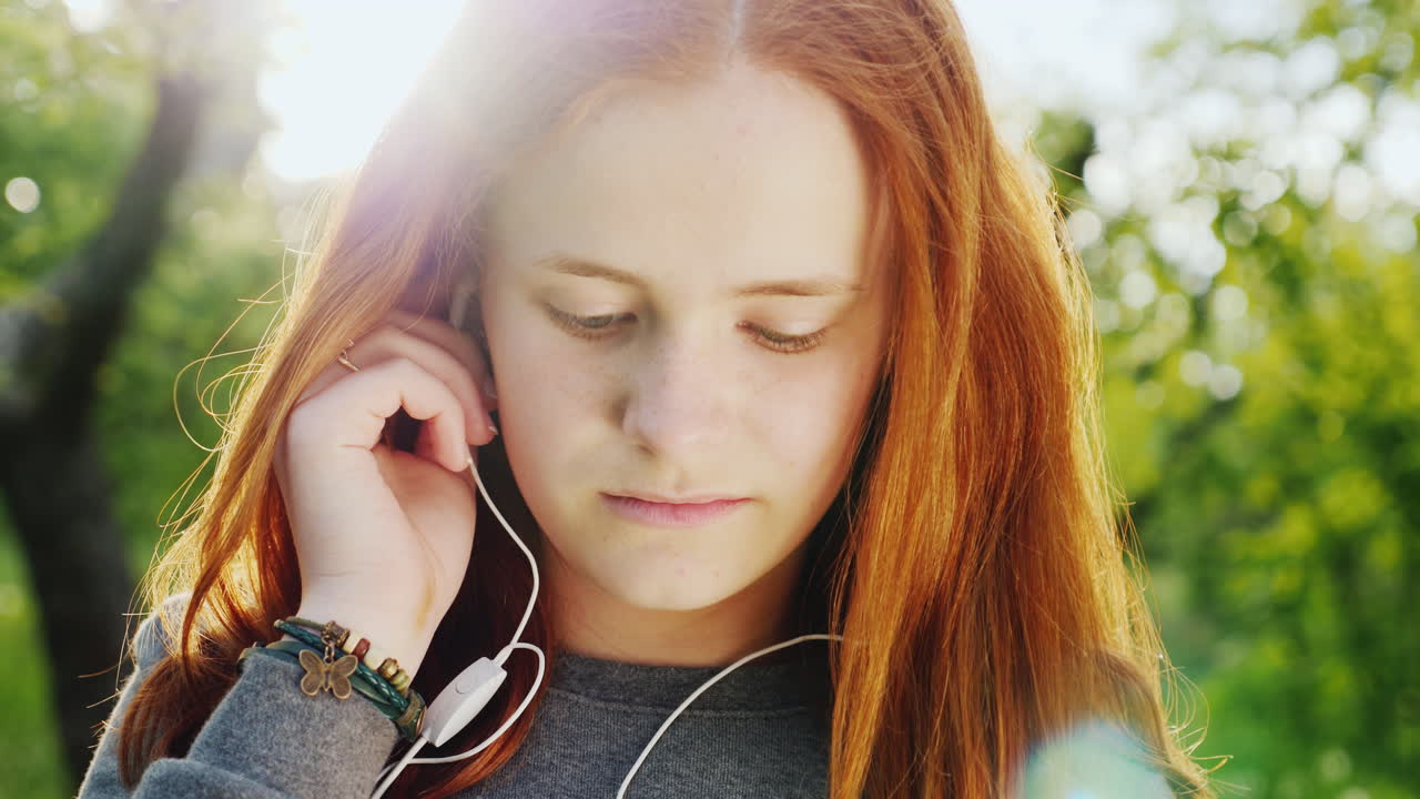 헤드폰 1에서 음악을 듣고 귀여운 빨간 머리 십 대 소녀