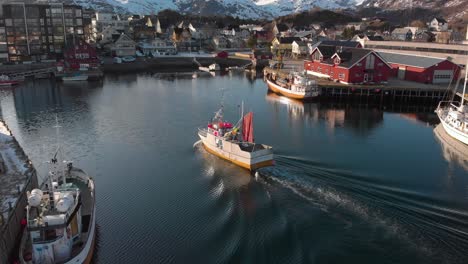 aerial drone shot of a small fishing boat going in to the docks in lofoten norway