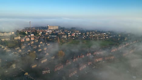 Luftaufnahmen,-Die-Den-Blick-Auf-Eine-Kleine-Stadt-Und-Grüne,-Mit-Nebel-Bedeckte-Felder-Während-Der-Wintersaison-Freigeben