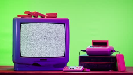 old television with grey interference screen on purple neon background. close-up of vintage tv and cartridges for retro playstation. antique video game, nostalgia
