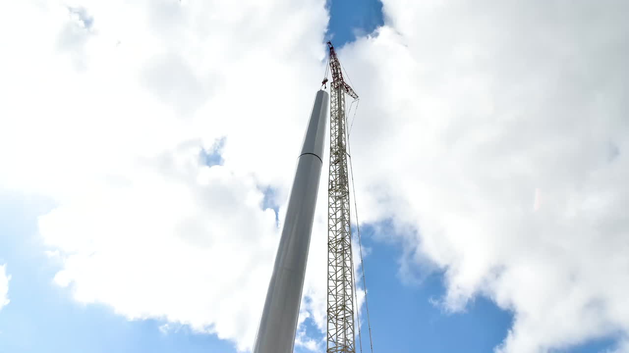 Daytime timelapse of a crane assembling a wind turbine in Israel. Partly cloudy, dynamic following shot.