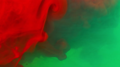 Green-And-Red-Paint-Or-Dye-Dropped-Into-Water-Against-White-Background-To-Create-Swirling-Colourful-Smoke-Background