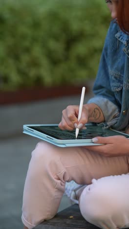 woman drawing on an ipad outdoors