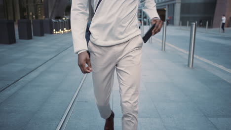 african american businessman walking through city using smart phone