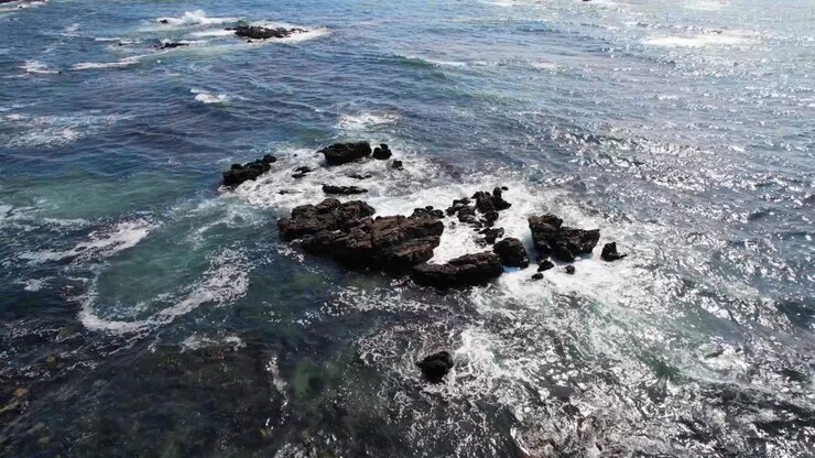 as ondas quebram as rochas num oceano azul.