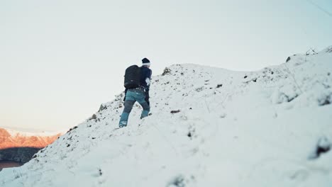 young man hiking uphill on a snow-covered mountain in hoddevik, norway