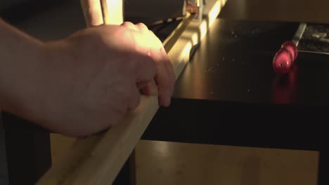 primer plano de enfoque estrecho: carpintero mide la madera en la mesa iluminada lateralmente