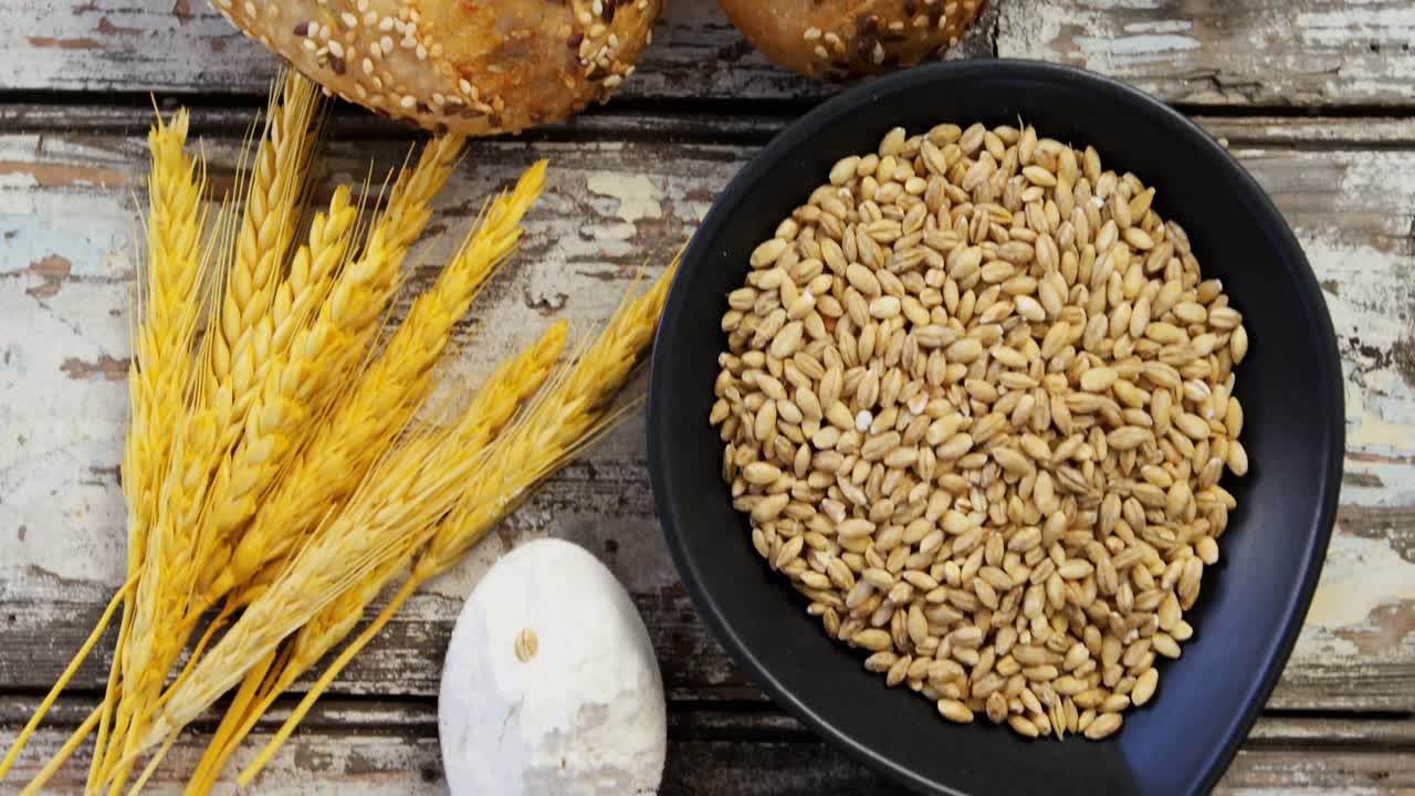 Wheat grains with bread buns, oats and spoon full of flour