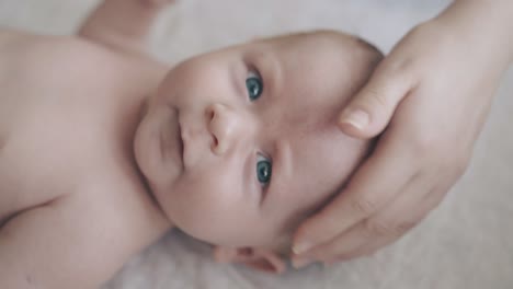 infant boy with fair hair and large blue eyes lies on table