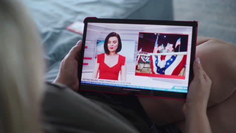 una mujer nos está viendo las noticias de las elecciones en una tableta.