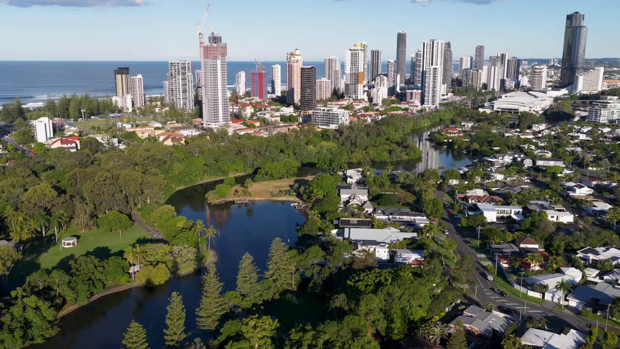 Aerial footage captures Gold Coast's skyline and lush greenery under bright daylight, showcasing urban and natural harmony