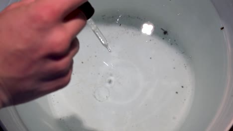 putting clear solution for the ph levels in a bucket of water -close up