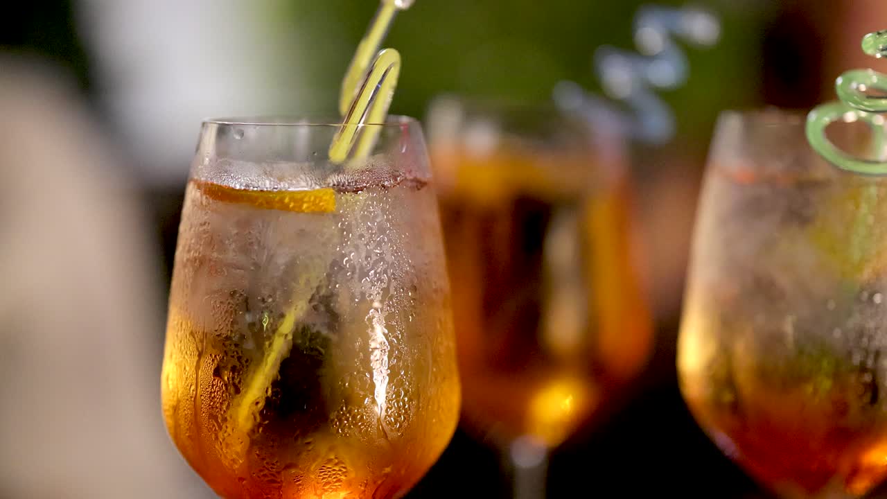 Close-up of citrus twist spiraling into frosty Negroni cocktail, vibrant lighting, shallow focus