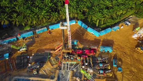 imágenes cinematográficas de drones de 4k de la estructura del equipo de la plataforma de perforación en tierra para la exploración y explotación de petróleo en medio de la jungla rodeada de palmeras durante la puesta de sol y el alto precio del petróleo
