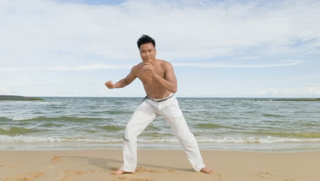 un tipo bailando capoeira en la playa.