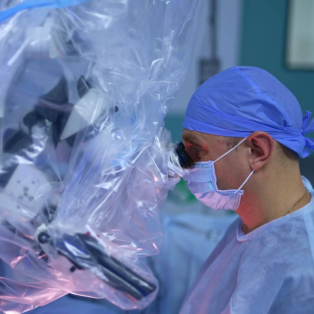Two male surgeons looking attentively into the binoculars of microscope in modern surgery room. Advanced equipment is covered in plastic