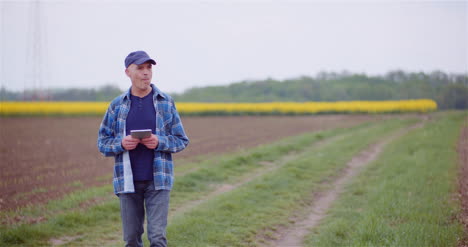 Farmer-Examining-Agricultural-Field-While-Working-On-Digital-Tablet-Computer-At-Farm-23