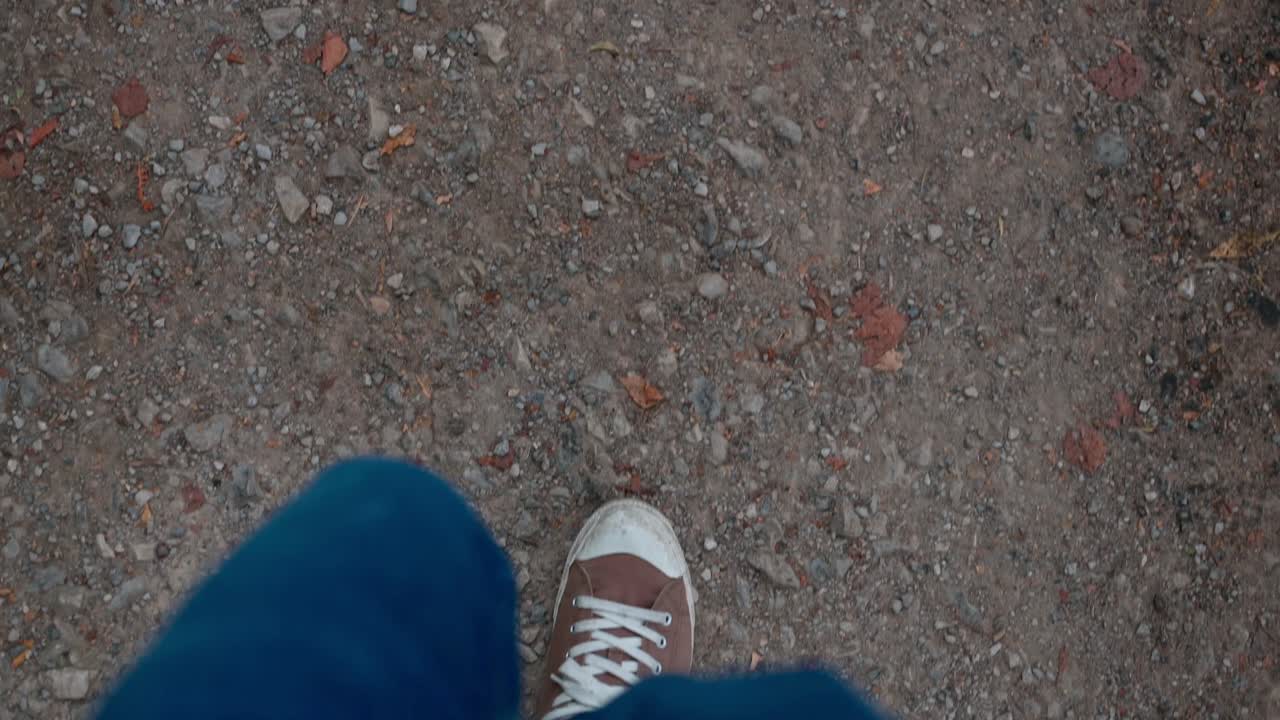 Çakıllı yolda yürüyüşün tepe çekimi, ağır çekim.