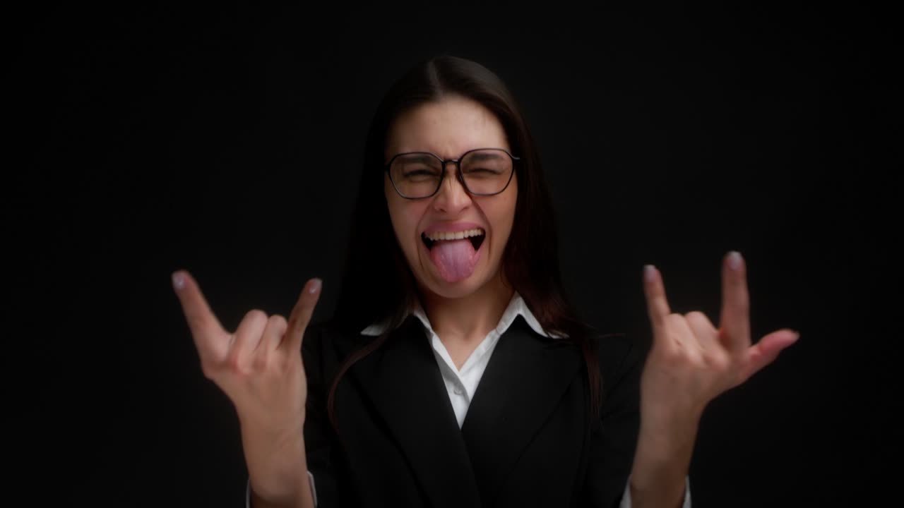 una joven y hermosa mujer de negocios muestra un símbolo de roca con sus manos.