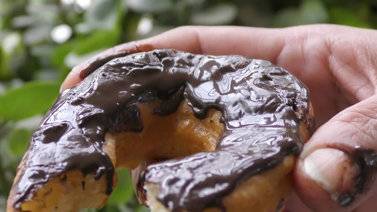 Dark chocolate doughnut in the hands and has been eaten
