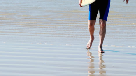 senior man with surfboard walking on beach