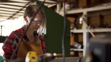 dolly right, woman in safety goggles studies plans for project in shop