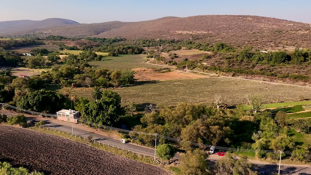 A rural landscape with hills, fields, and a road passing through, aerial view