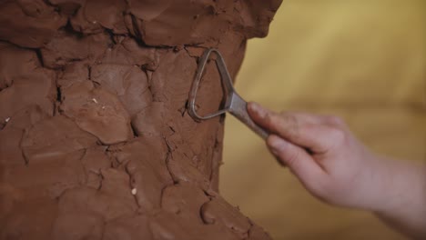 un hombre está esculpindo una pieza de arcilla, sus manos hábilmente moldeando y dando forma al material