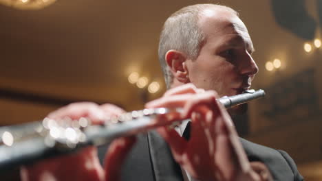talentoso flautista de mediana edad está tocando la flauta en la sala filarmónica concierto de la orquesta sinfónica