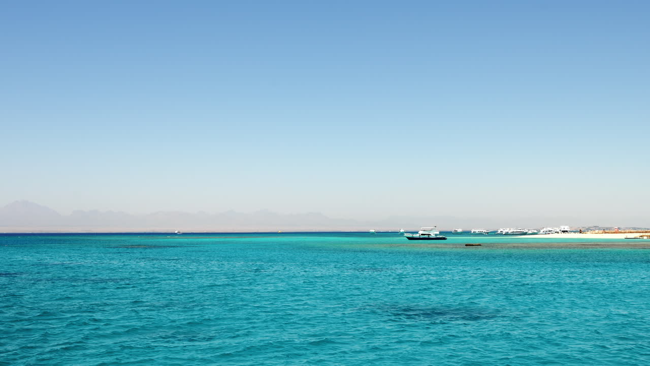 이집트 후르가다의 오렌지 베이 해변, 맑고 푸른 물과 관광객을 태우는 보트선, 60fps