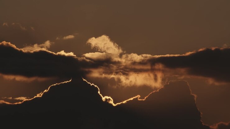 Time lapse of sun setting behind clouds at sunset, static wide shot